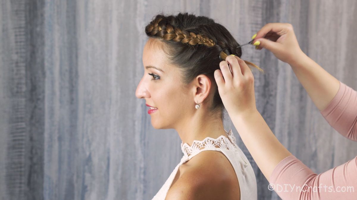 french braid crown being secured on brunette