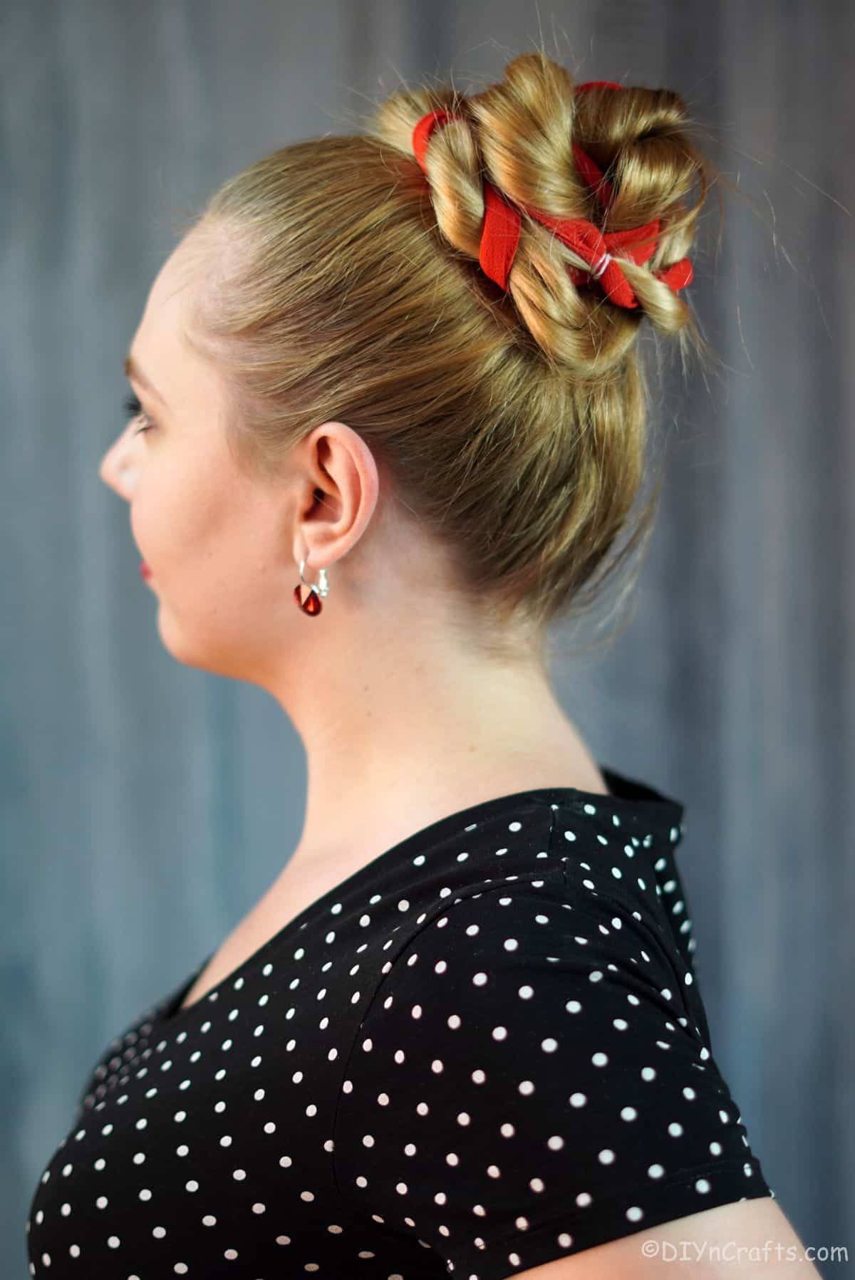 high twisted bun with red ribbon on blonde woman in black