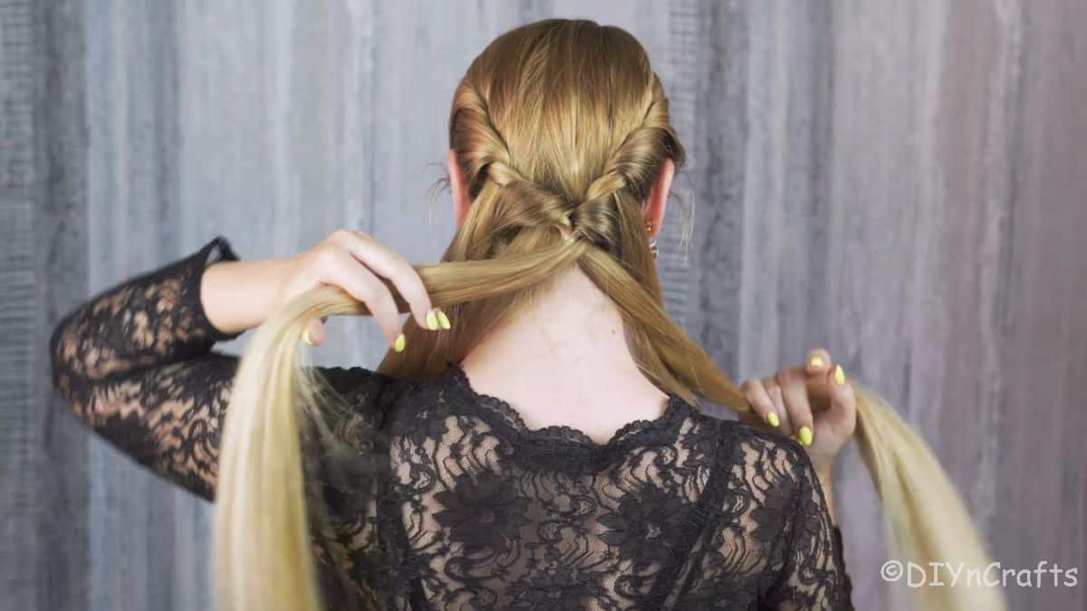 blonde woman braiding her hair behind her head