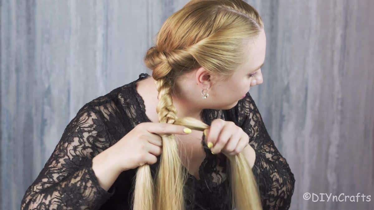 blonde woman braiding her hair