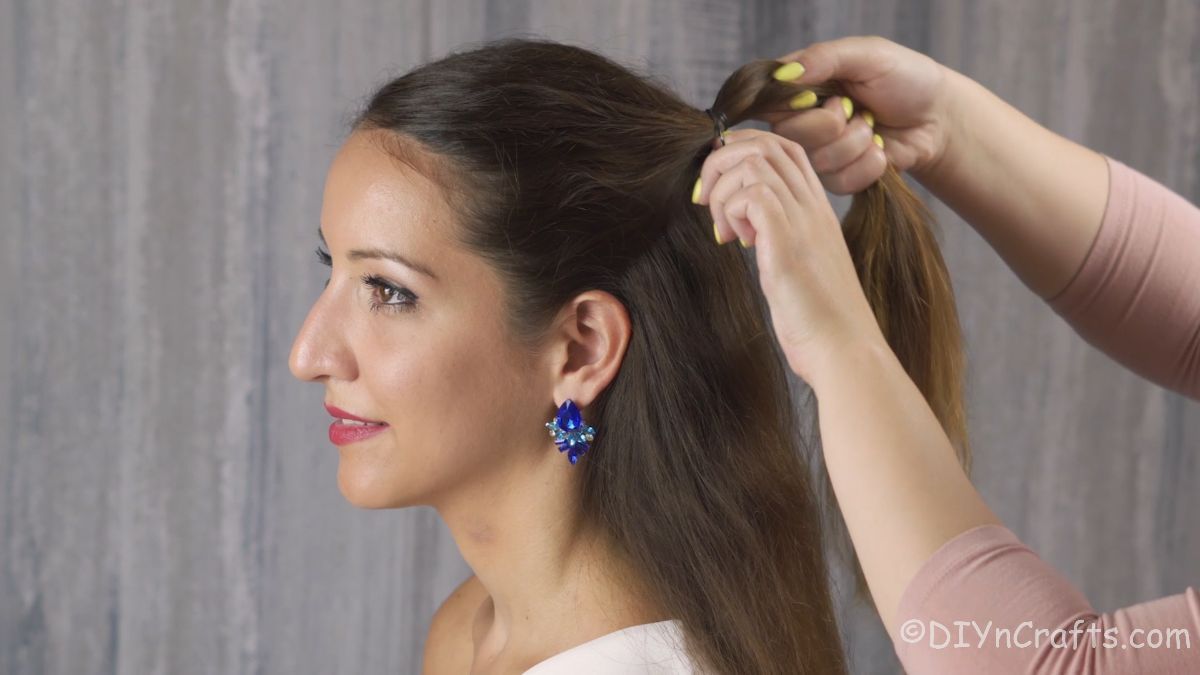 woman pulling hair from front of temple into ponytail