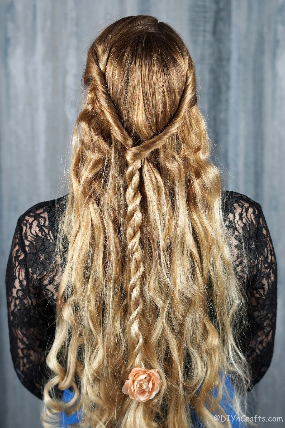 back of half up braided hairstyle on blonde in black shirt