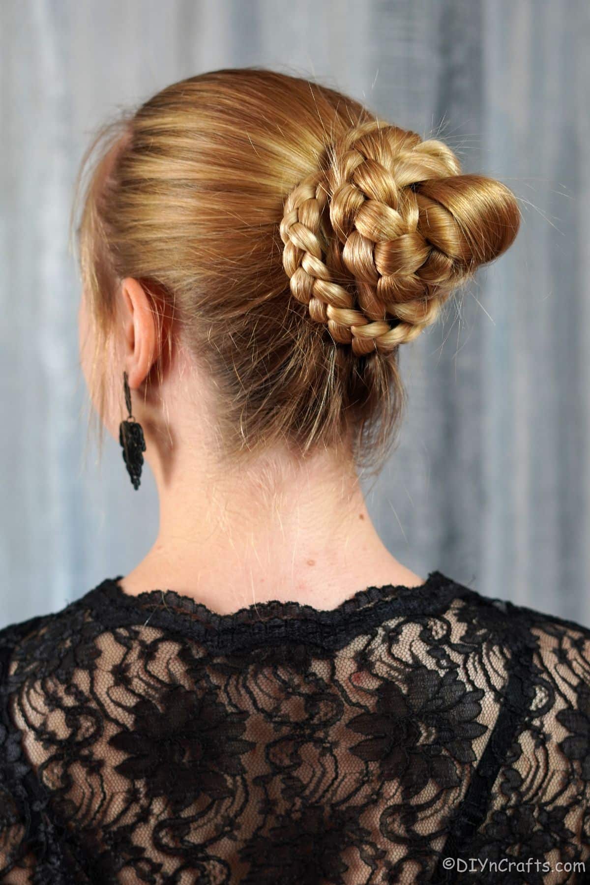 woman in black lace shirt with twisted braid bun