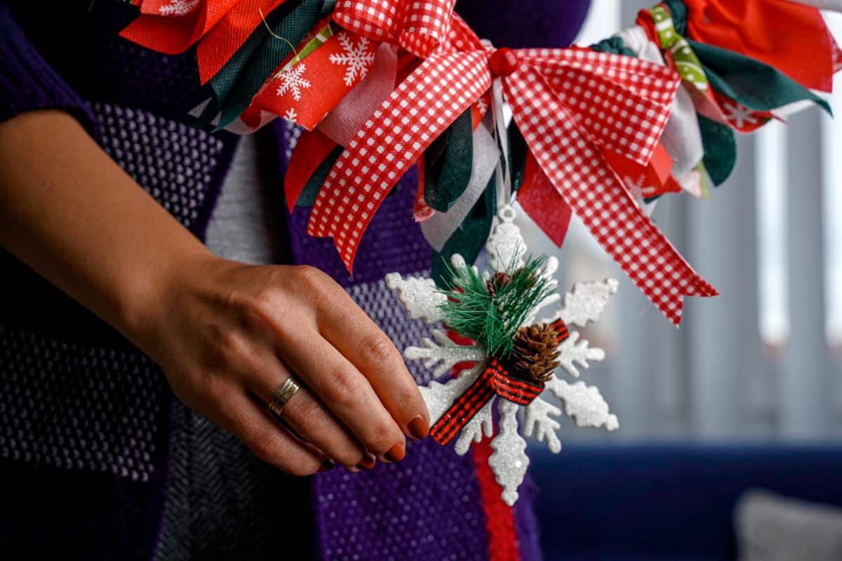 woman in purple holding wreath with white sparkle snowflake accent