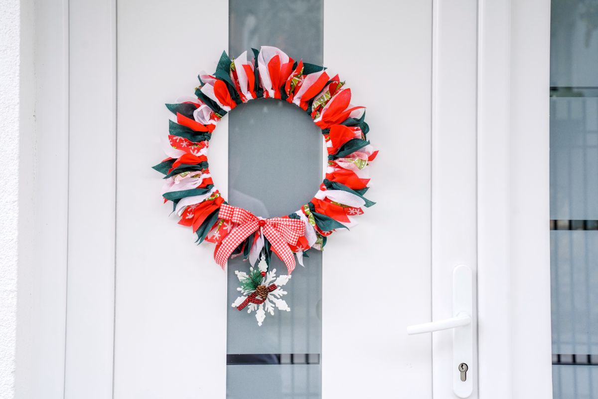 Christmas wreath on white door with snowflake hanging on bottom of wreath