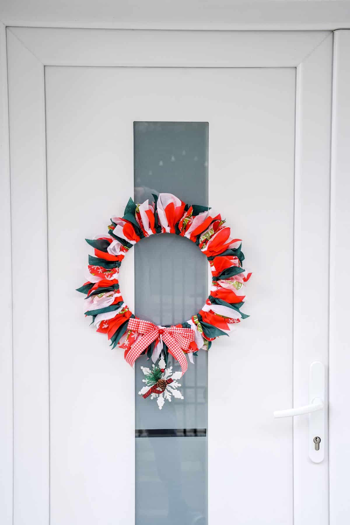 white door with center glass panel holding a Christmas rag wreath