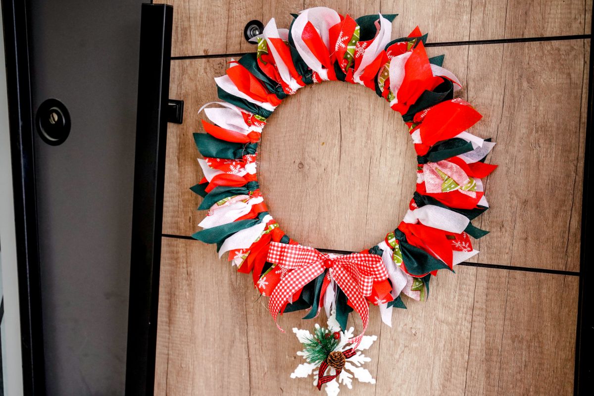 red, green, and white Christmas wreath hanging on wood paneled wall