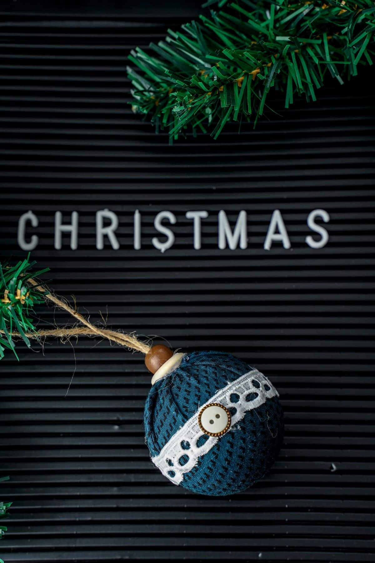 Black Christmas sign with fake garland and round fabric ornament