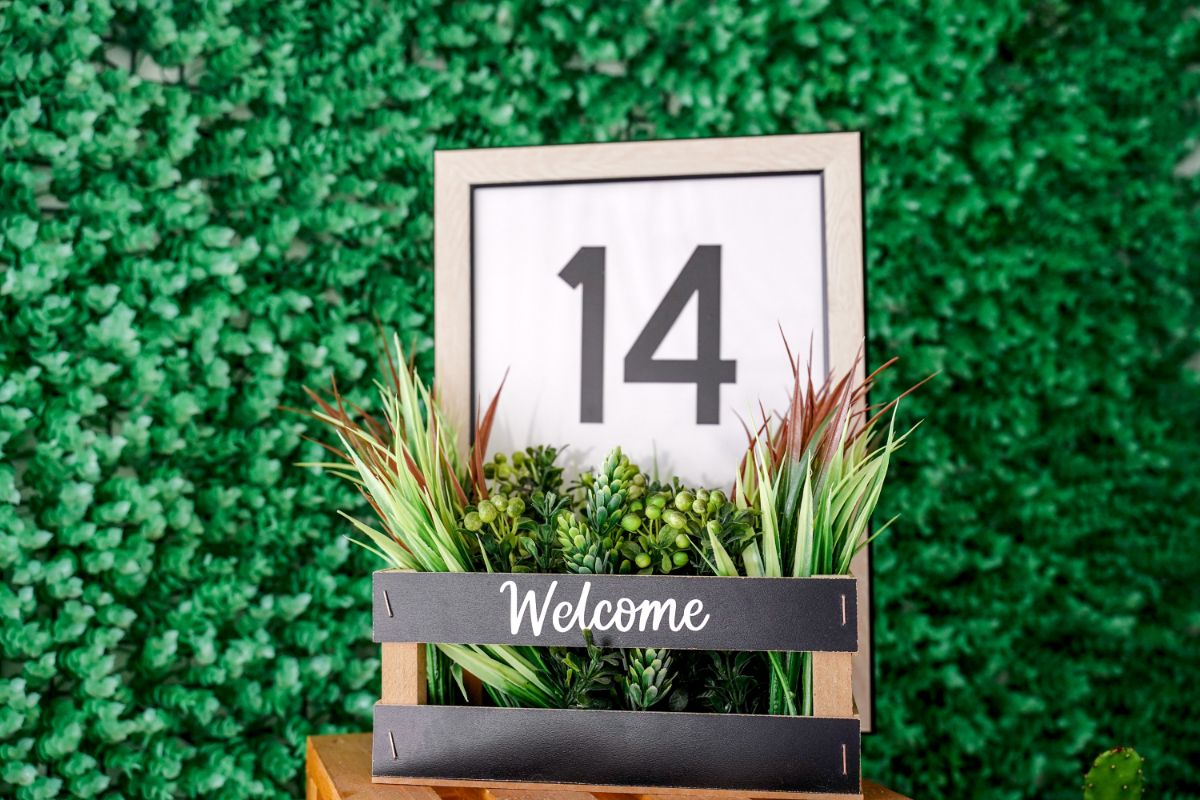 framed house number sign with basket holding fake greenery in front