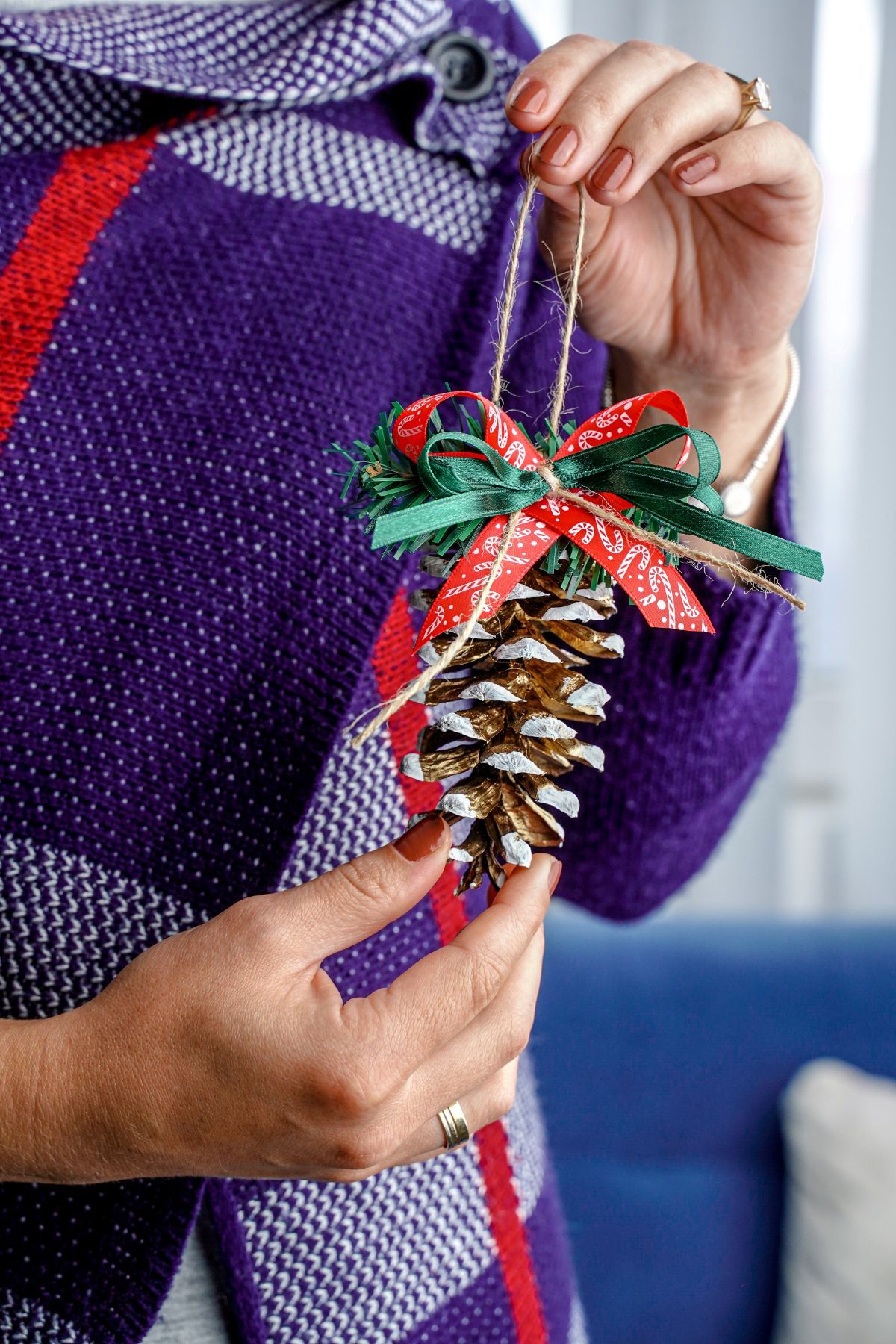 woman in purple sweater holding pinecone ornament