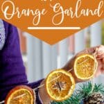 holding a dried fruit holiday garland with text which reads the easiest diy dried orange garland